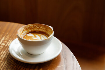 Cup of hot milk latte coffee on table by the window.
