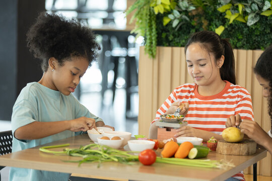 group of multi-ethnic children girls are learning how to cooking with miniature kitchen utensils, teamwork student education up skill make food.