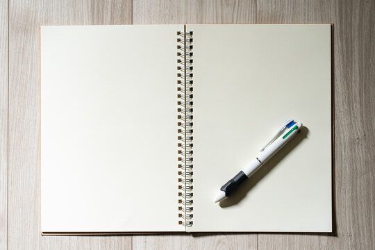 Open notebook with multi-color pen on wooden floor