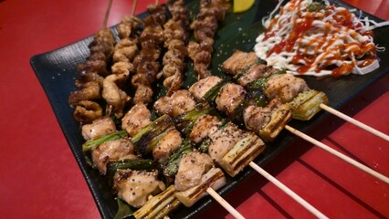Assorted grilled chicken skewers including crispy chicken skin and juicy meat, served with sauce.