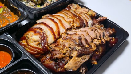 Sliced Korean jokbal served in a takeout tray, highlighting the glossy texture and sesame topping.