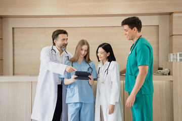 Caucasian woman doctor use tablet computer with team working at hospital	