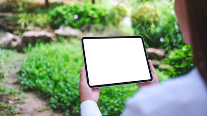Mockup image of a woman holding digital tablet with blank white desktop screen in the nature outdoors
