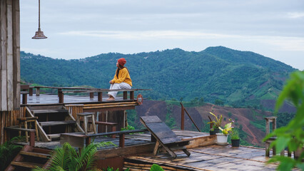 A woman sitting on wooden terrace and looking at a mountain view