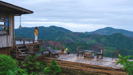 A woman standing on wooden terrace and looking at a mountain view
