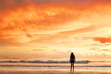 Behind tween girl  on beach watching beautiful  orange  sunset A