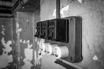 Old Electrical Switches and Peeling Paint on a Wall - monochrome