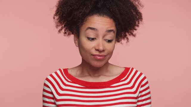 Woman shrugging with uncertain facial expression on pink