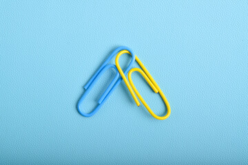 Two paper clips isolated on light blue background