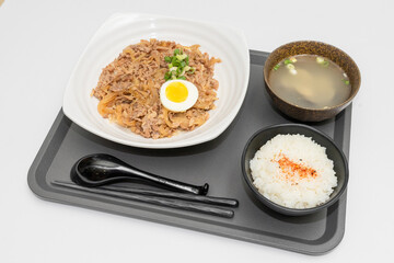 A Thai basil minced pork set meal arranged on a tray, including a portion of stir-fried spicy basil pork, a bowl of steamed white rice, three side vegetables, and a bowl of soup. The presentation refl