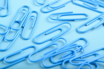 Many blue paper clips isolated on light blue background