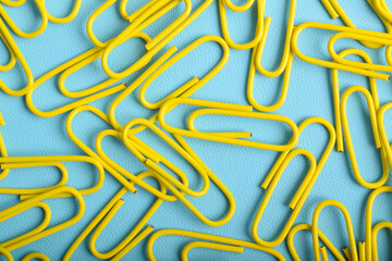 Many yellow paper clips isolated on light blue background, flat lay