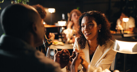 Conversation, date and holding hands with couple in restaurant at night for bonding or celebration....