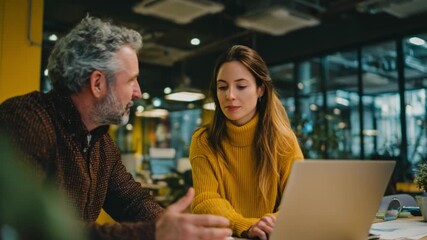 Collaborative Insight: Two colleagues engage in focused discussion, exchanging ideas and knowledge as they work together on a project, highlighting the power of teamwork and open communication.