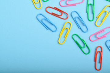 Colorful paper clips isolated on light blue background. Copy space. Copy space for your text and information