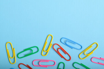 Colorful paper clips isolated on light blue background. Copy space. Copy space for your text and information