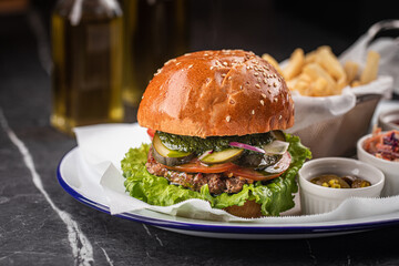 Tasty cheeseburger with fries, sauces and salad on white plate
