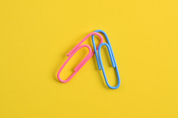 Two paper clips isolated on yellow background