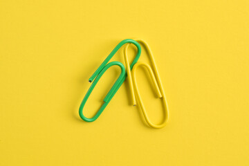 Two paper clips isolated on yellow background