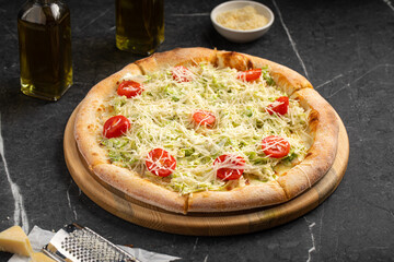 Caesar pizza with cherry tomatoes, lettuce and grated cheese on wooden board
