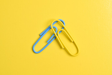 Two paper clips isolated on yellow background