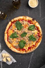 Hot mince pizza with spinach leaves and cheese on black stone background