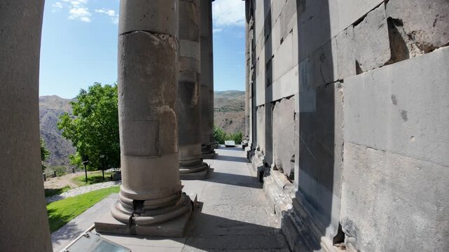 Sunlight illuminating the colonnade of Garni Temple highlights the intricate Hellenistic architecture while framing a picturesque landscape in Armenia