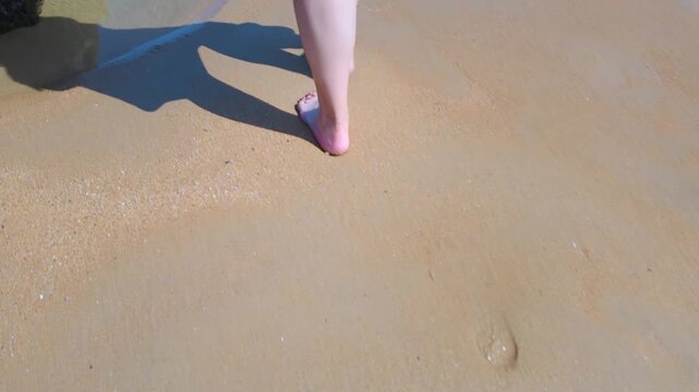 A woman's feet walking among the rocks and sand of the beach of Costa Quebrada, Cantabria, Spain.