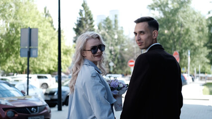 A bride and groom in love walking along a city street in summer