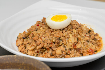 A Thai basil minced pork set meal arranged on a tray, including a portion of stir-fried spicy basil pork, a bowl of steamed white rice, three side vegetables, and a bowl of soup. The presentation refl