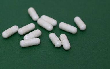 pills on a green background, white capsules
