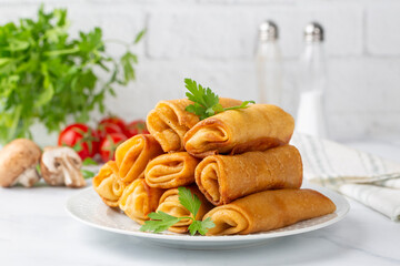 Pancakes or thin crepes stuffed with chicken and mushrooms on a plate