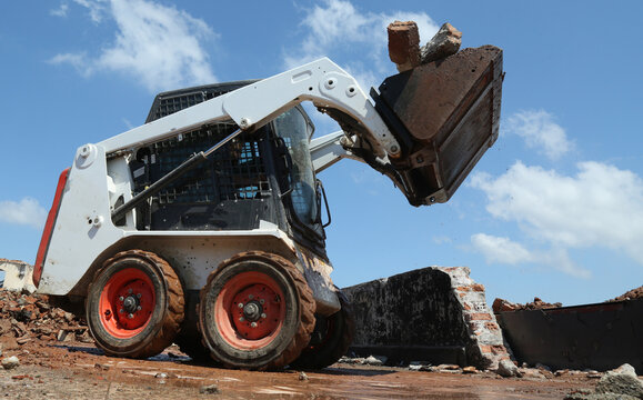 skid steer loader working construction site. mini loader transports excavation waste at construction site. compact loader. skeed steer workingi on site. compact construction machinery.