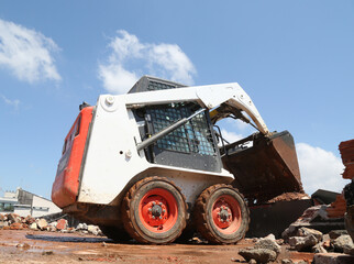 skid steer loader working construction site. mini loader transports excavation waste at...
