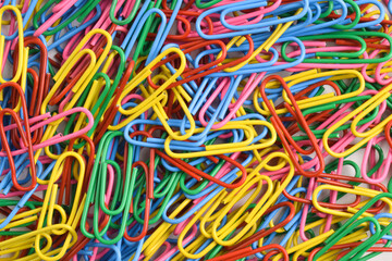 Pile of colorful paper clips on white background, top view