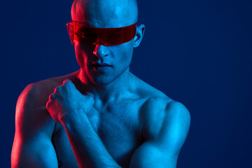 A powerful man with futuristic sunglasses poses dramatically against a vibrant blue background,...