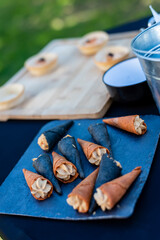 Unique dessert cones with creamy filling displayed at an outdoor gathering during a sunny day