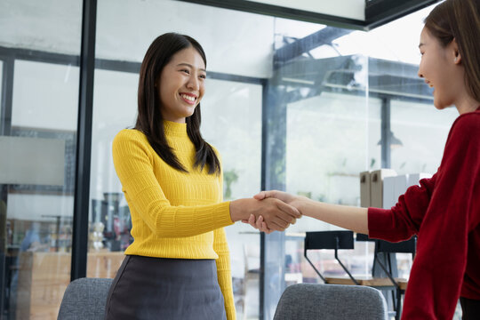 Asian business woman shaking hands in meeting room.
