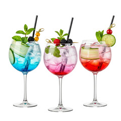 Three colorful gin tonic cocktails with ice, cucumber, mint, and berries offer a refreshing and vibrant beverage experience.