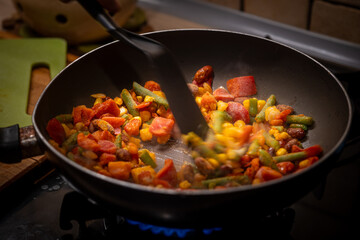 Preparing a healthy, balanced meal: frying frozen vegetables and chicken in a pan. Nutritious cooking, clean eating, and wholesome diet concept for a healthy lifestyle