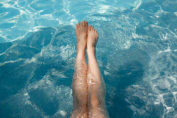 A girl's feet in a blue pool. Epilation of legs, varicose veins. Rest, relaxation on the beach, at the hotel. A woman in freedom. Vacation. High quality photo