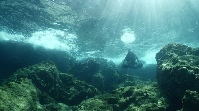 scuba diver howers like budha underwater with waves under sun beams and rays yogo meditation