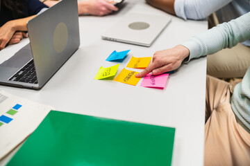 Business team analyzing marketing strategy using colorful sticky notes during a meeting in a modern...