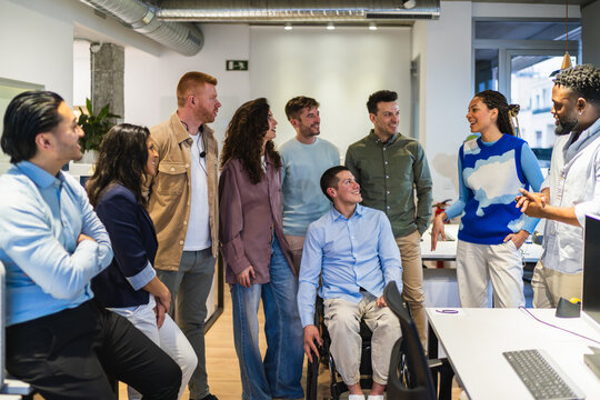 Creative professionals collaborating on a project in a modern office, demonstrating teamwork and inclusion with a colleague using a wheelchair - Powered by Adobe