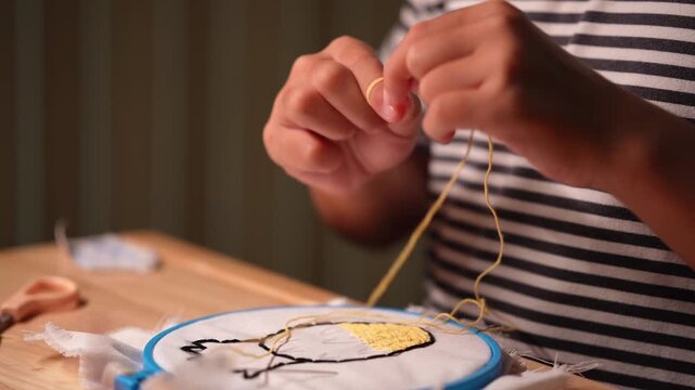 Close-up of a girl's hand embroidering a circle of embroidery with a frame. Girl person handmade craft sewing pattern on canvas.