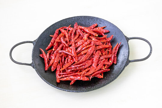 Vibrant dry red chillies on a tava ready for aromatic frying. Ideal for showcasing Asian food preparation, cooking spices, and healthy recipe ingredients in high-quality stock photos.