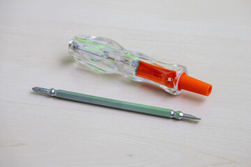Dual purpose electric voltage tester star and flat tips. Multi-tester for 100-500V range. Accurate voltage test driver on a wooden surface.