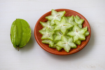 Vibrant star fruit slices, Averrhoa carambola or Kamranga, meticulously arranged on a traditional...