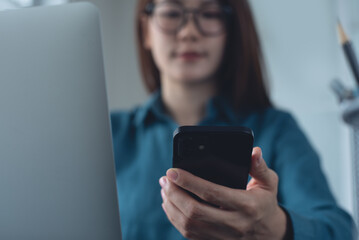 Business woman using mobile phone and working on laptop computer at office. Woman online working on laptop computer and using smartphone searching the information, surfing the internet