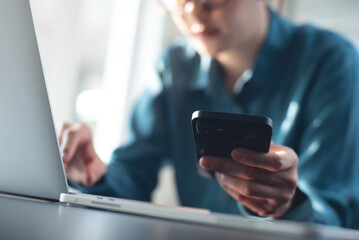 Close up, business woman working on laptop computer and using mobile phone at office. Woman typing...